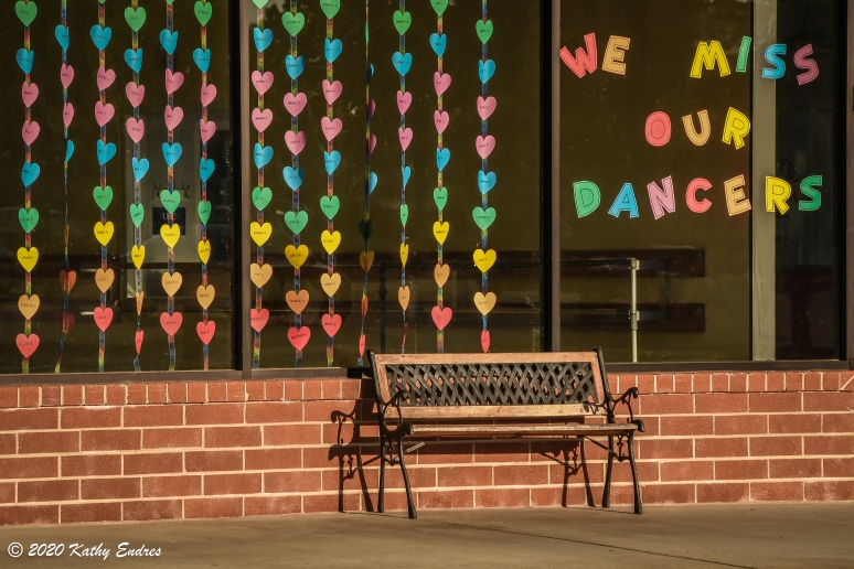 Many of us missed attending our group activities when states locked down. This storefront message shows how instructors likewise missed seeing their dancers, who were each represented by a colored heart. The feeling of melancholy is also characterized by the empty bench in this photo.